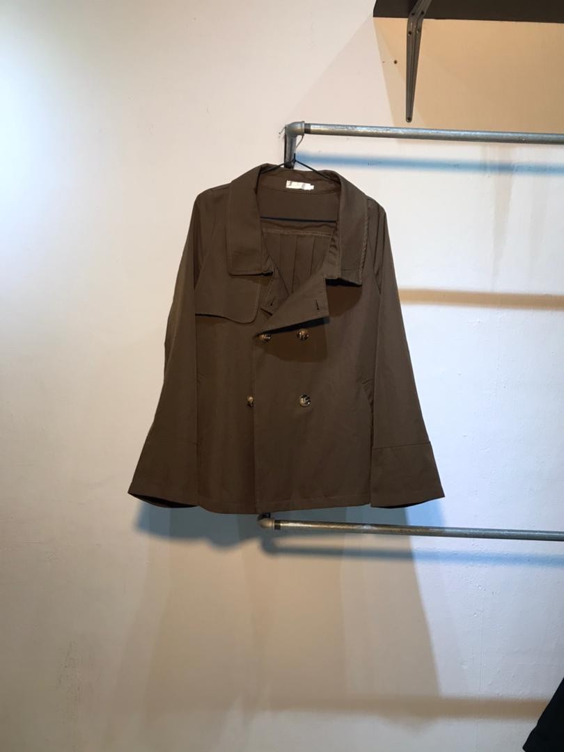 SPIRAL STORE brown double-breasted trench coat with wide lapels and pleating detail on the chest.