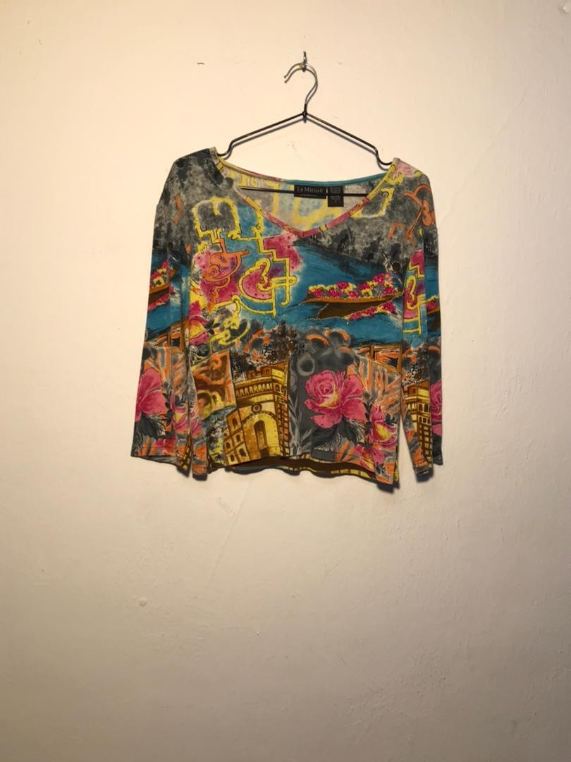 SPIRAL STORE long sleeve v-neck top with a vibrant floral and architectural print in pink, yellow, blue, and grey.